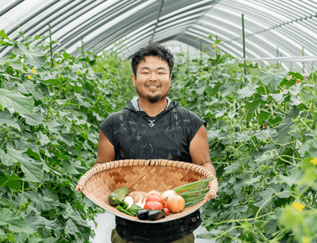 新鮮な野菜が入ったかごを持つ笑顔の男性